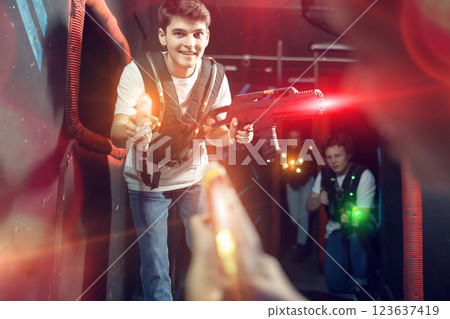 Portrait of positive man with laser gun having fun with her friends on lasertag arena Portrait of positive man with laser gun having fun with her friends on lasertag arena 123637419