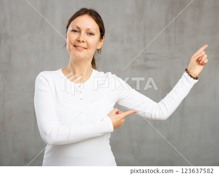 Cheerful woman with wide grin on her face exuding happiness and positivity pointing Cheerful woman with wide grin on her face exuding happiness and positivity pointing 123637582