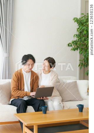 A couple looking at a personal computer in the living room A couple looking at a personal computer in the living room 123638136