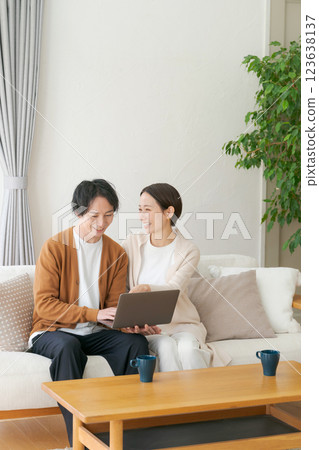 A couple looking at a personal computer in the living room A couple looking at a personal computer in the living room 123638137