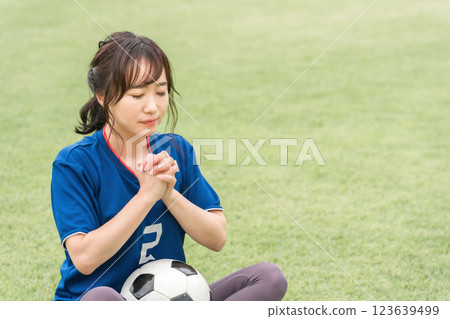 A Japanese woman who is a soccer fan and supporter cheering for the Japan national team as if praying 123639499