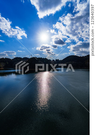 The temperature is rising and it's starting to feel like spring at Nara Nunome Dam. The beautiful lake surface reflects the clouds floating in the blue sky. The temperature is rising and it's starting to feel like spring at Nara Nunome Dam. The beautiful lake surface reflects the clouds floating in the blue sky. 123640397