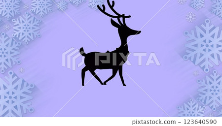 Black silhouette of reindeer walking over snowflakes forming a frame against purple background 123640590