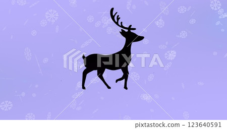 Black silhouette of reindeer walking over snowflakes falling against purple background 123640591