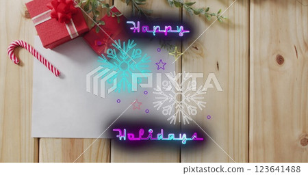 This image is a digitally generated image of neon happy holiday text and snowflakes on a black backg 123641488
