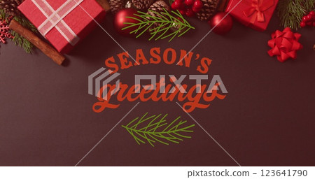 Image of seasons greetings text banner with leaves icon over christmas decorations and gifts 123641790