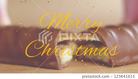 Image of golden stars and merry christmas banner against close up of a chocolate bar 123641813