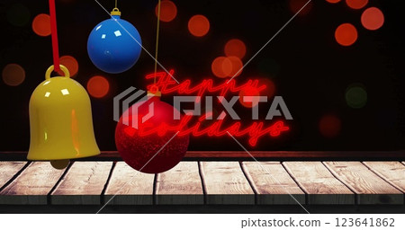 Image of illuminated red happy holidays text and lens flares with colorful baubles over table 123641862