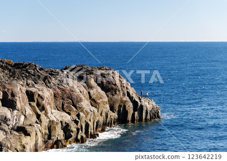 Man fishing at the tip of a rock Man fishing at the tip of a rock 123642219