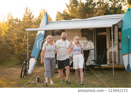 Family enjoys camping adventure near their camper van with surfboards in a natural setting during golden hour Family enjoys camping adventure near their camper van with surfboards in a natural setting during golden hour 123642272