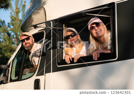Family enjoying a scenic road trip in their camper van during a sunny afternoon in a beautiful natural setting 123642301