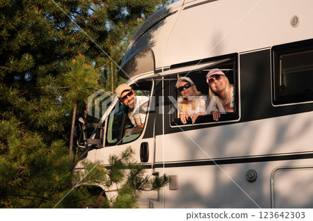 Family enjoying a scenic road trip in their camper van during a sunny afternoon in a beautiful natural setting 123642303