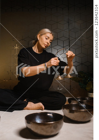 Practicing mindfulness and meditation with singing bowls in a serene indoor setting during the evening 123642314