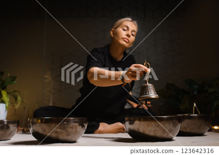 Practicing mindfulness and meditation with singing bowls in a tranquil indoor setting during a holistic wellness session 123642316