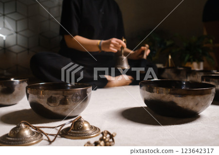 Practicing mindfulness and meditation with singing bowls in a tranquil indoor setting during a holistic wellness session Practicing mindfulness and meditation with singing bowls in a tranquil indoor setting during a holistic wellness session 123642317