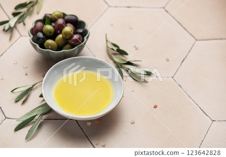 Olive oil and olives with olive branches resting on a tiled surface 123642828