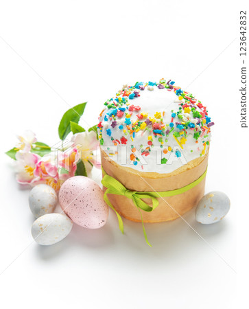Easter cake with colorful sprinkles, decorated eggs, and spring flowers on white background 123642832