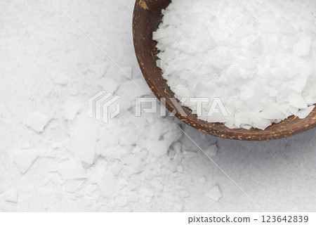 Magnesium chloride flakes in a small dark wooden bowl  123642839