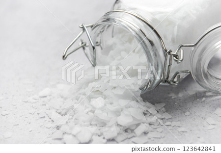 Magnesium flakes spilling from a glass jar onto a gray surface Magnesium flakes spilling from a glass jar onto a gray surface 123642841