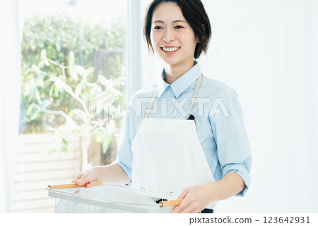 A woman holding a laundry basket 123642931