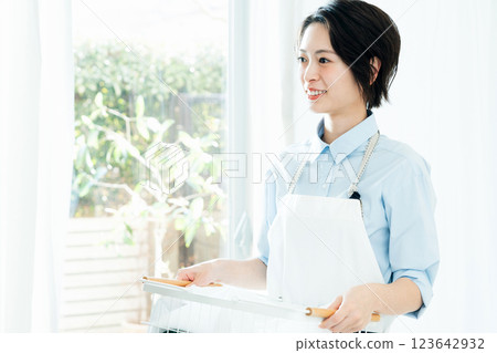 A woman holding a laundry basket 123642932