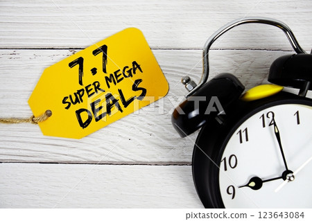 7.7 Super Mega Deals Promotion on price tag with alarm clock on wooden background 7.7 Super Mega Deals Promotion on price tag with alarm clock on wooden background 123643084