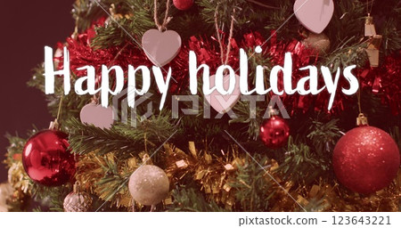 Happy holidays text in white over decorations on christmas tree 123643221