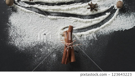 Cinnamon sticks tied with string lie amidst flour on a dark surface 123643223