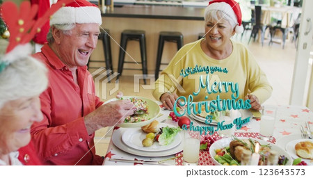 Image of christmas greetings text over senior diverse friends at christmas meal table 123643573