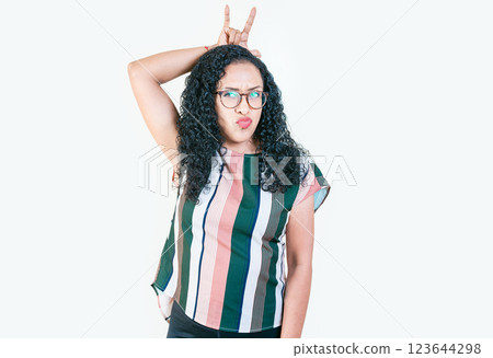 Young afro girl making horns gesture with fingers. Afro girl making horns gesture with their fingers, gesture of betrayal. Infidelity concept 123644298
