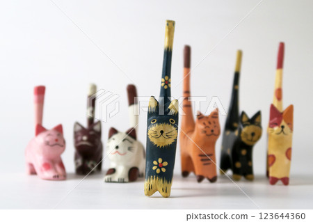 Folk craft wooden carved cats lined up in a row on a white background Folk craft wooden carved cats lined up in a row on a white background 123644360