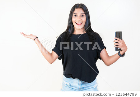 Happy latin girl holding phone and looking at camera. Cheerful young girl holding smartphone and smiling at camera Happy latin girl holding phone and looking at camera. Cheerful young girl holding smartphone and smiling at camera 123644799