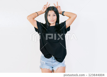 Young girl making horns gesture with their fingers, gesture of betrayal. Young woman making horns gesture with fingers. Infidelity concept Young girl making horns gesture with their fingers, gesture of betrayal. Young woman making horns gesture with fingers. Infidelity concept 123644804