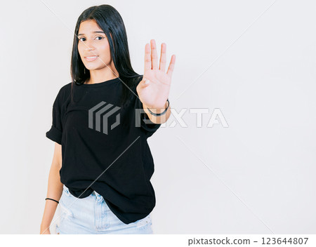 Teen girl gesturing stop with palm hand isolated. Young woman rejecting with the palm of hand isolated. People gesturing stop isolated 123644807