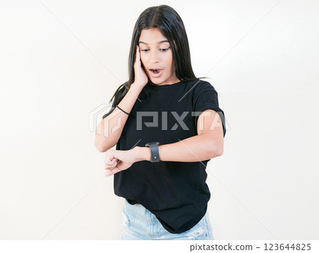 Surprised young woman looking at wrist watch. Worried young woman looking at her watch isolated 123644825