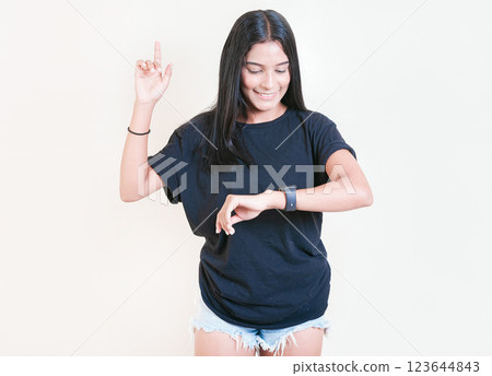 Smiling teen girl looking at hand watch isolated. Happy young woman looking at hand watch isolated 123644843