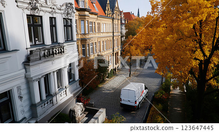White cargo van in an old European city with autumn foliage White cargo van in an old European city with autumn foliage 123647445