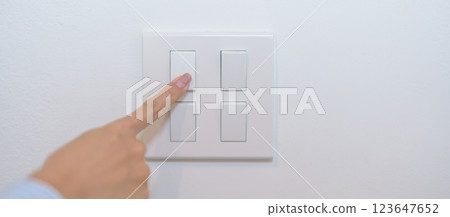 Female finger pushing for turn on light switch on white wall at home room. Woman hand turn off lighting Switch. Energy Saving, energy power control, electrical, eco environment, and lifestyle concept 123647652