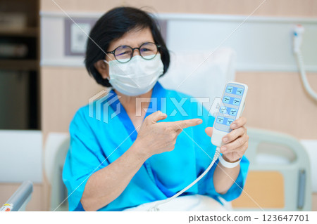 Elderly asian Woman patient hand using remote control for adjust level bed in hospital room. Happy Senior illness resting on comfortable electric bed in modern hospital 123647701