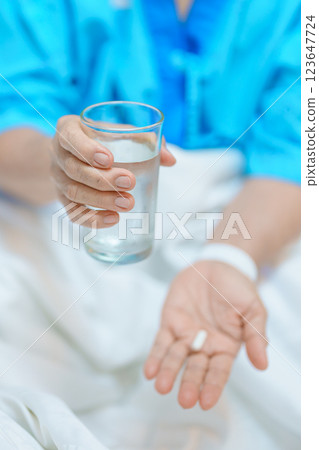 Elderly asian Patient Woman hold pill and glass of fresh water. Female Senior take medicine tablets in hospital. Influenza, Fever, illness, treatment, Insurance, Healthcare, medical and Medicine day 123647724