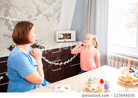 A young Caucasian mother plays Easter games with her daughter. A kitchen decorated for the holiday for children's games 123648030