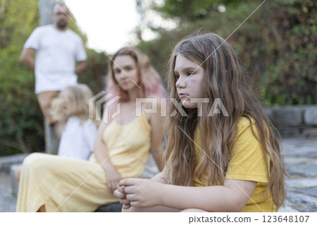 Sad girl feeling excluded from family gathering outdoors 123648107