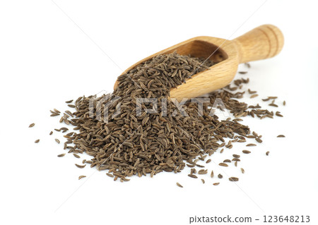 Caraway seeds spilling from wooden scoop on white background 123648213