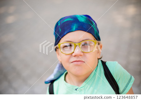 A playful small boy in glasses and a headband, dressed in a green shirt and jean shorts, laughing A playful small boy in glasses and a headband, dressed in a green shirt and jean shorts, laughing 123648857