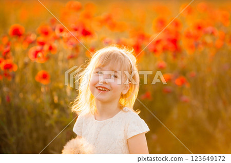 A cheerful blonde girl in a poppy field, collecting flowers and having fun 123649172