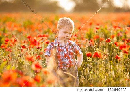 A young boy with crossed eyes is playing in a field, discovering different plants A young boy with crossed eyes is playing in a field, discovering different plants 123649331