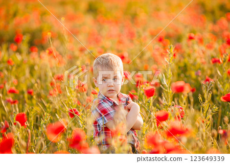 A young boy with crossed eyes is playing in a field, discovering different plants A young boy with crossed eyes is playing in a field, discovering different plants 123649339