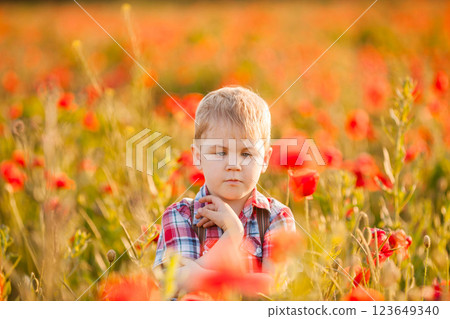 A small boy with an eye condition enjoys exploring the plants while playing in the field 123649340