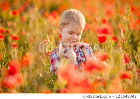 A young boy with crossed eyes is playing in a field, discovering different plants 123649342