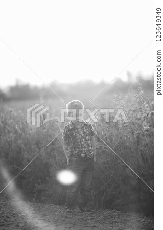 A funny young boy with eye misalignment, smiling and giggling in a sunset-lit poppy field A funny young boy with eye misalignment, smiling and giggling in a sunset-lit poppy field 123649349